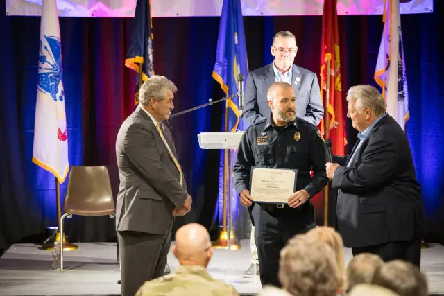 A police officer receives a certificate on stage