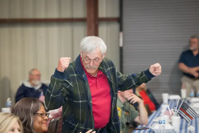 A guest raises both fists in celebration at his table